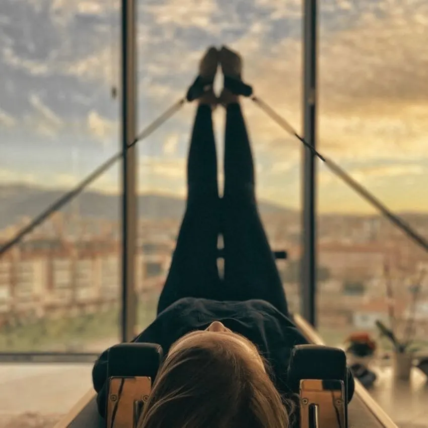 A woman doing pilates in front of a window with a view
